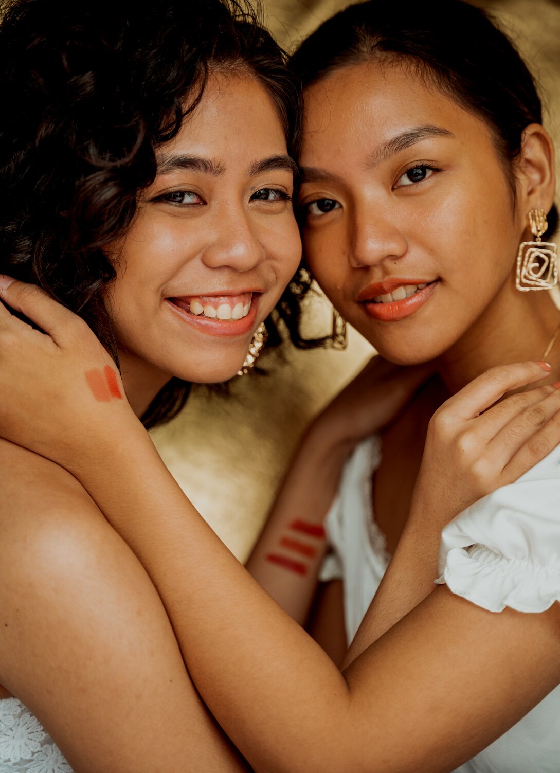 Smiling Women with Makeup Swatches on Hands